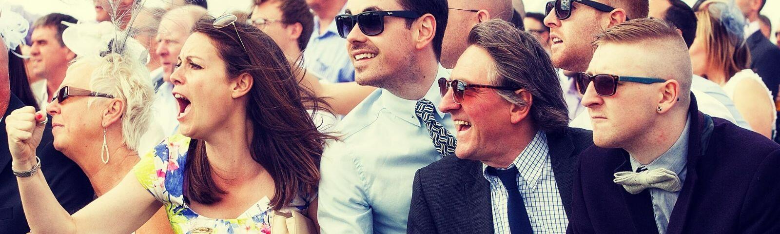 Crowds cheering whilst enjoying a day at the races