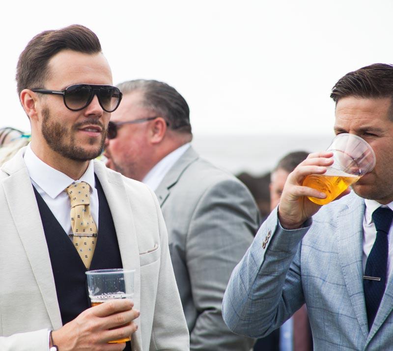 Two men dressed in suits drinking beer.