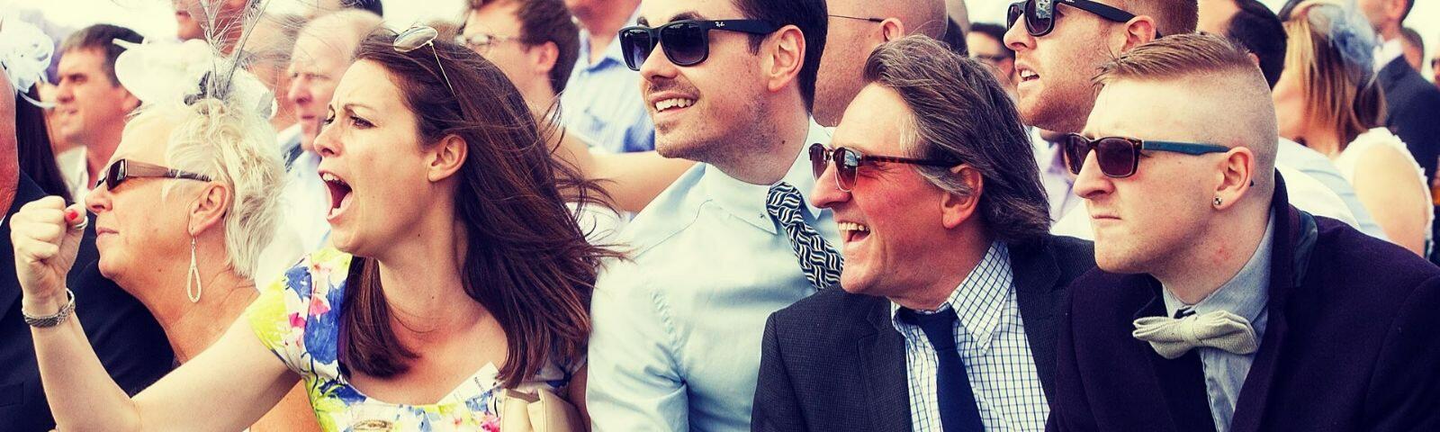 Crowds cheering whilst enjoying a day at the races